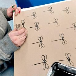 Person holding cardboard with scissor drawings, preparing to cut shapes for a craft activity.
