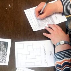 Person drawing Zentangle patterns on 'Strip Zentangles' and 'Square Zentangles' worksheets with completed designs nearby.
