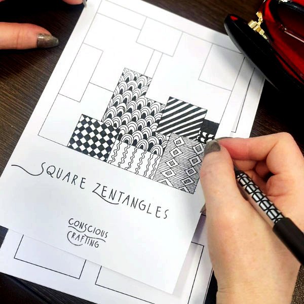 erson drawing black-and-white patterns in square sections on a 'Square Zentangles' template from Conscious Crafting.