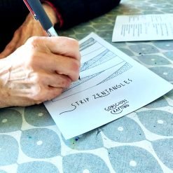 Person drawing intricate patterns on a 'Strip Zentangles' worksheet from Conscious Crafting.