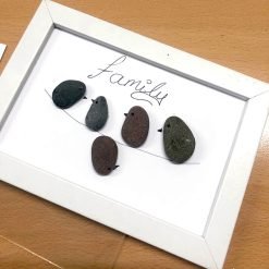 Framed pebble art of five birds on a branch with 'family' written above in cursive.