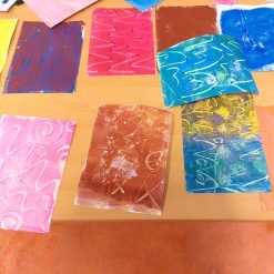 Colorful abstract prints with swirling and zigzag patterns laid out on a wooden table.