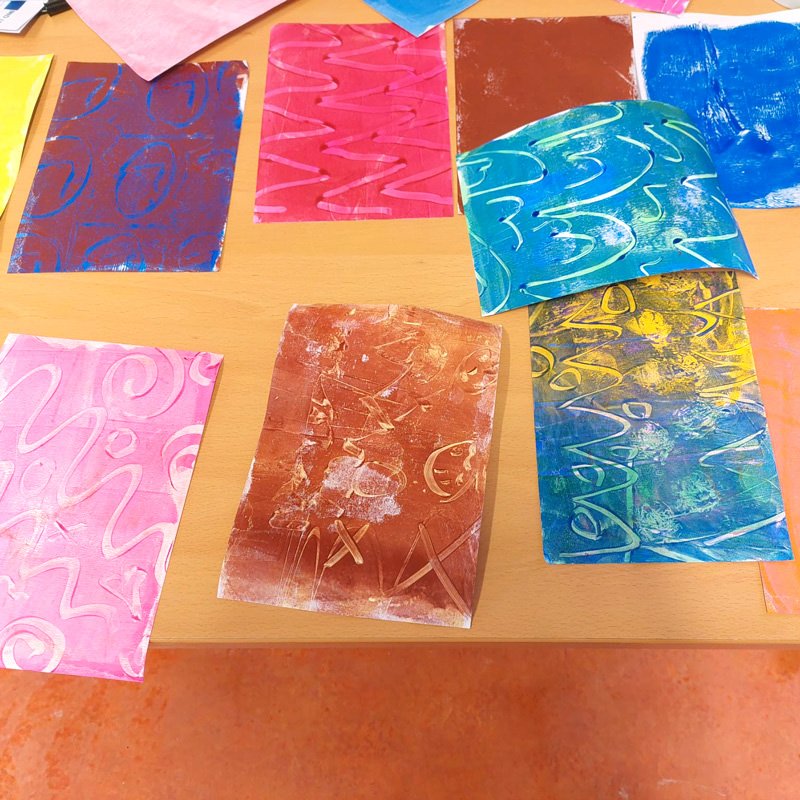 Colorful abstract prints with swirling and zigzag patterns laid out on a wooden table.