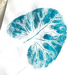Blue leaf print on white paper showing detailed veins and circular structure from pressing technique.