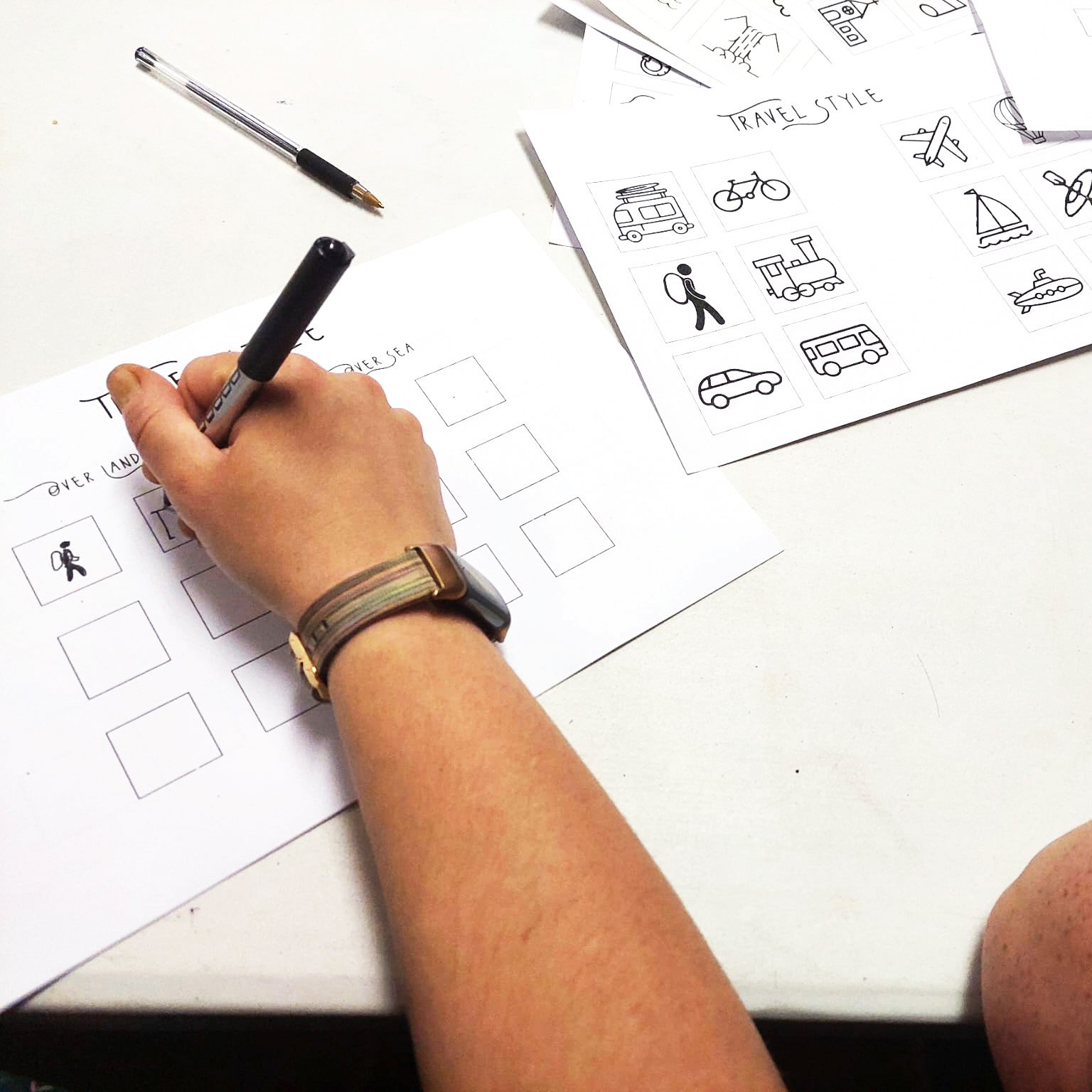 Person filling squares on a 'Travel Style' worksheet with icons for land and sea travel modes.